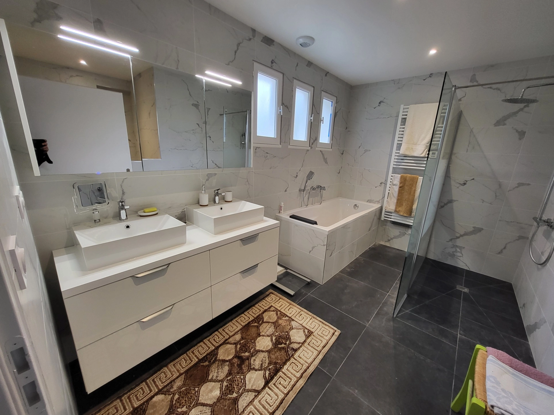 Salle de bain avec baignoire en marbre et armoire de toilette avec miroir intégré