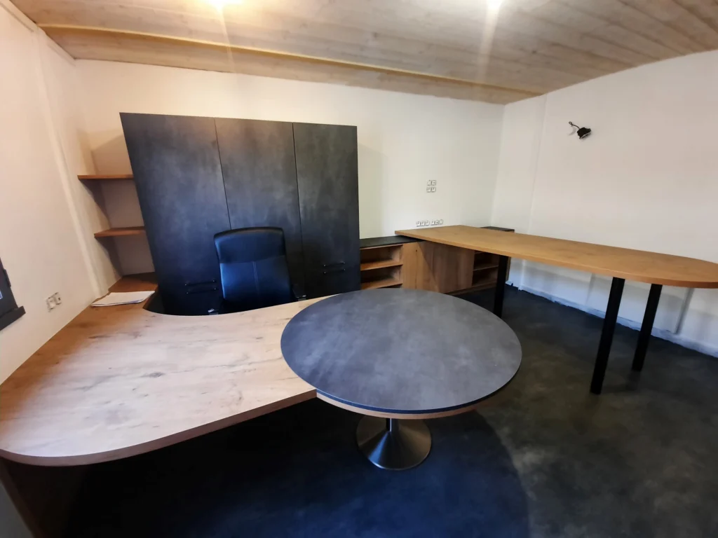Salle de réunion avec grandes tables de bureaux en bois et meuble de rangements gris foncé