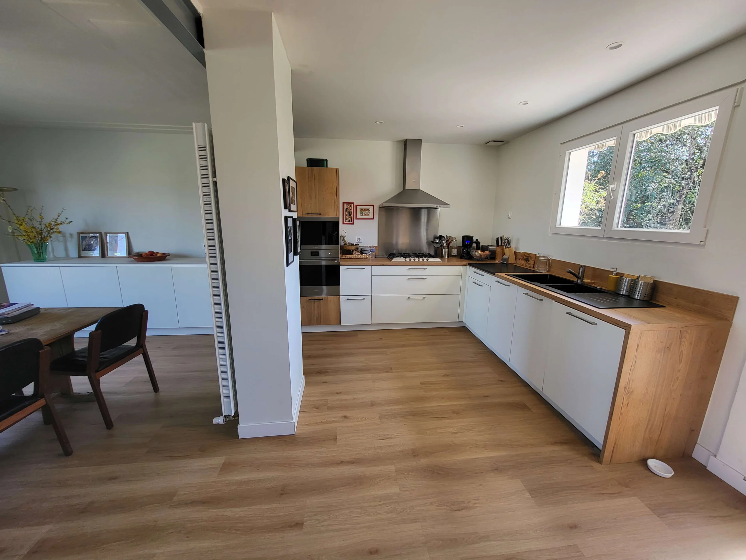 Cuisine ouverte blanche et en bois, ouverte en continuité avec la salle à manger