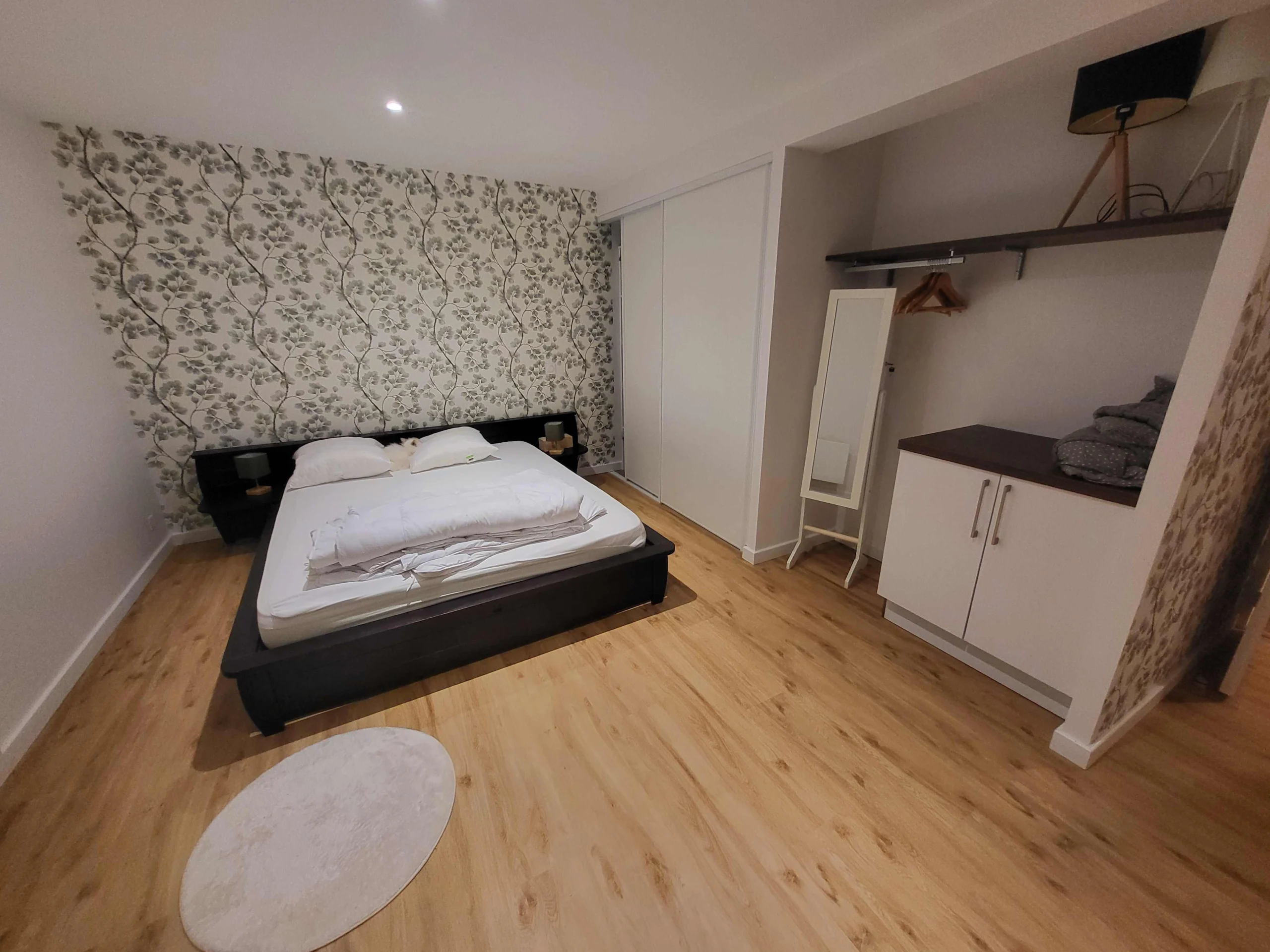 Chambre d'amis avec un lit au centre, un placard à portes coulissantes et un espace de rangement